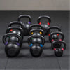 Set of black kettlebells with color-coded handles on a dark floor.