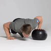 Person performing push-ups on a slam ball against a gray background