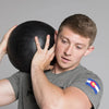 Person holding a black slam ball against a gray background