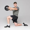 Man performing a lunge with a slam ball on a gray background