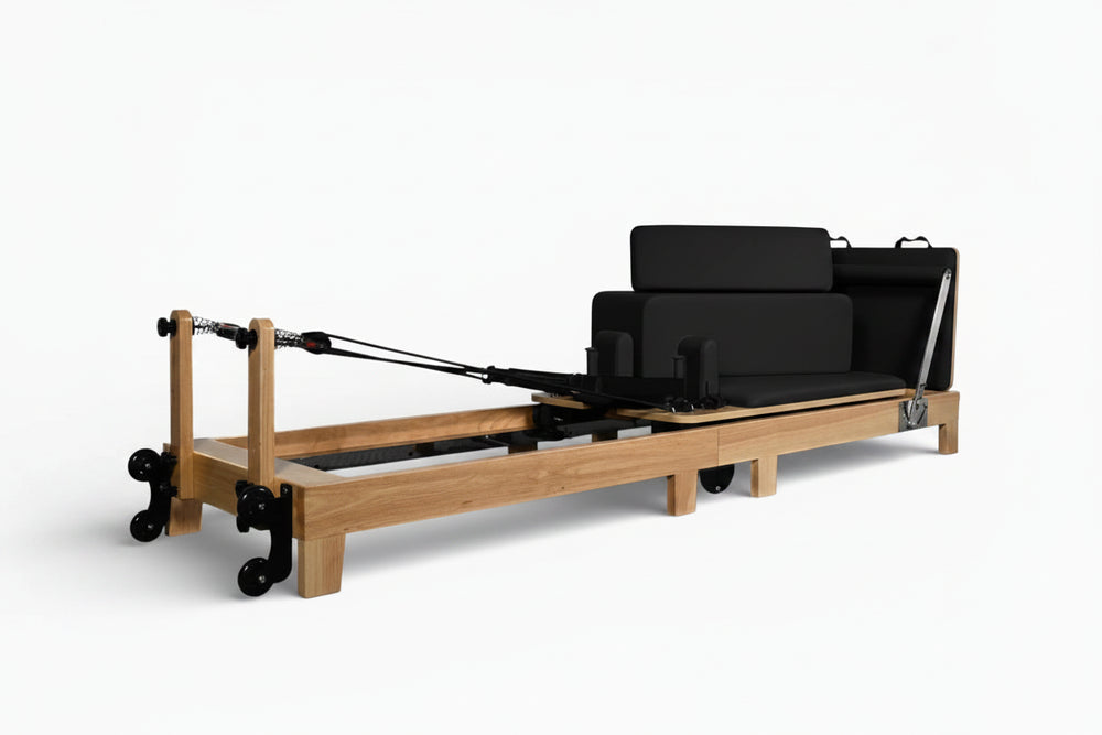 Wooden reformer exercise machine with black cushion on a white background