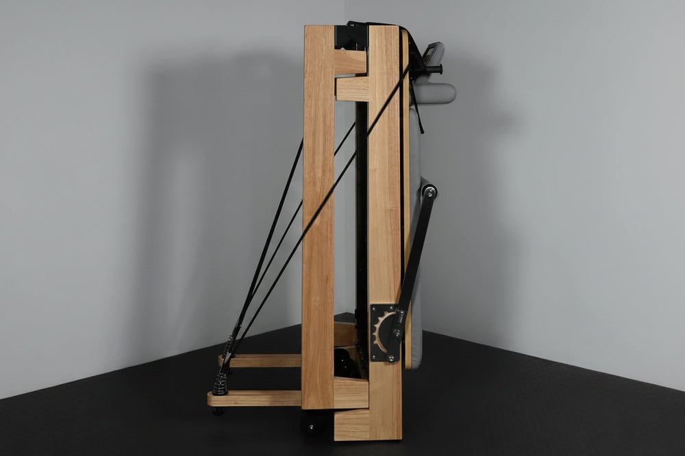 Wooden pilate reformer machine with in a folded position on a gray background