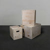 Three wooden jump boxes of different sizes stacked on a dark surface with a gray background