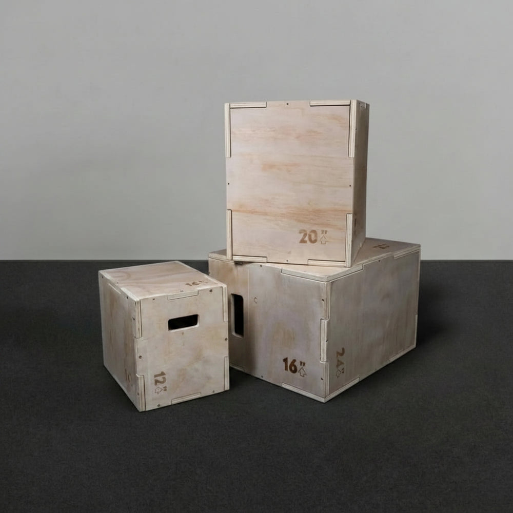 Three wooden jump boxes of different sizes stacked on a dark surface with a gray background