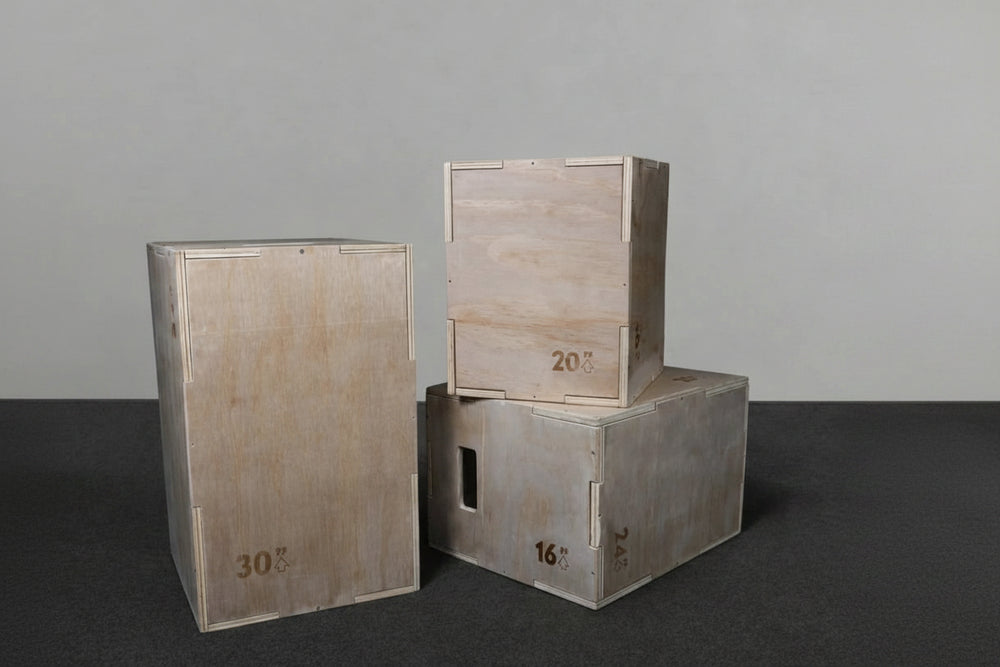 Three wooden jump boxes of different sizes stacked on a dark surface with a gray background