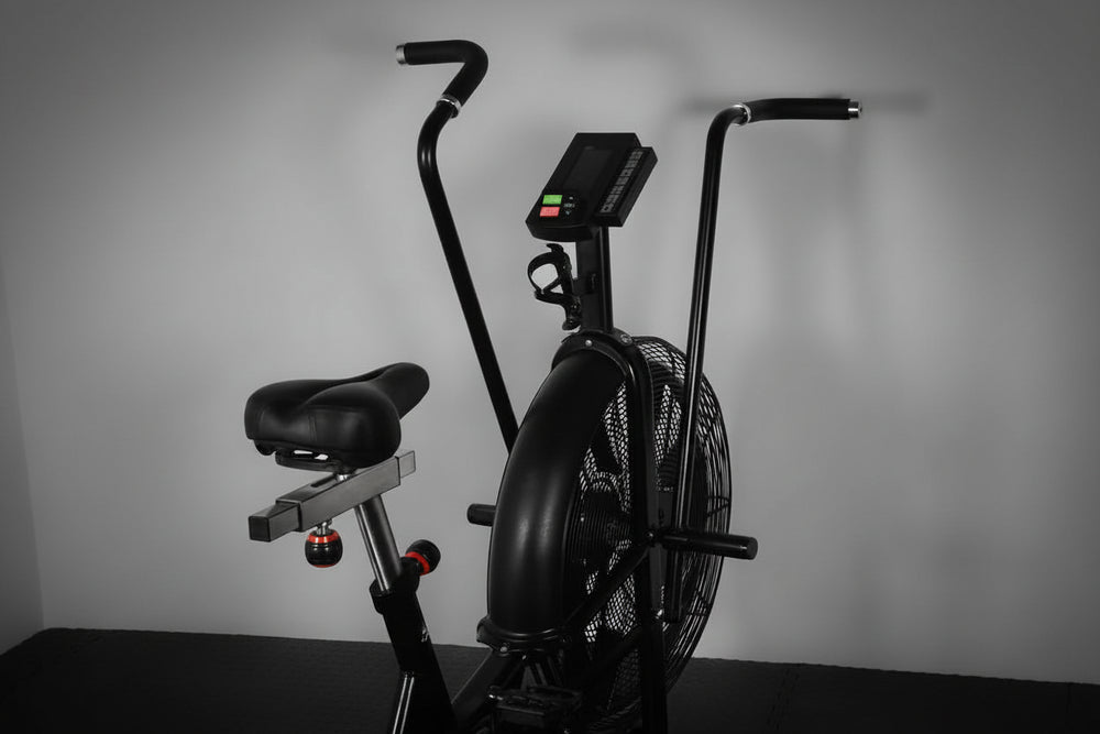 Black exercise bike with digital display on a gray background
