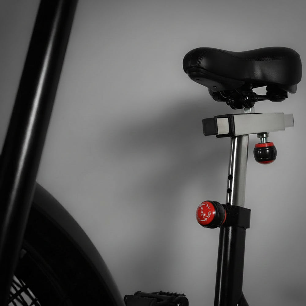 Close-up of a assault air bike with a black seat and red components on a gray background