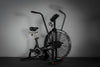 Black exercise air bike on a dark surface against a gray background