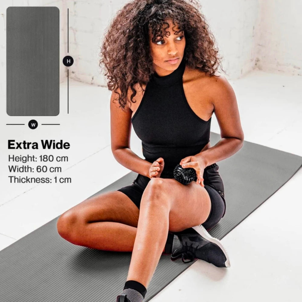 Woman sitting on a gray extra-wide yoga mat with product details on the side.
