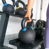 Person picking up a black kettlebell with blue accents off a kettlebell rack