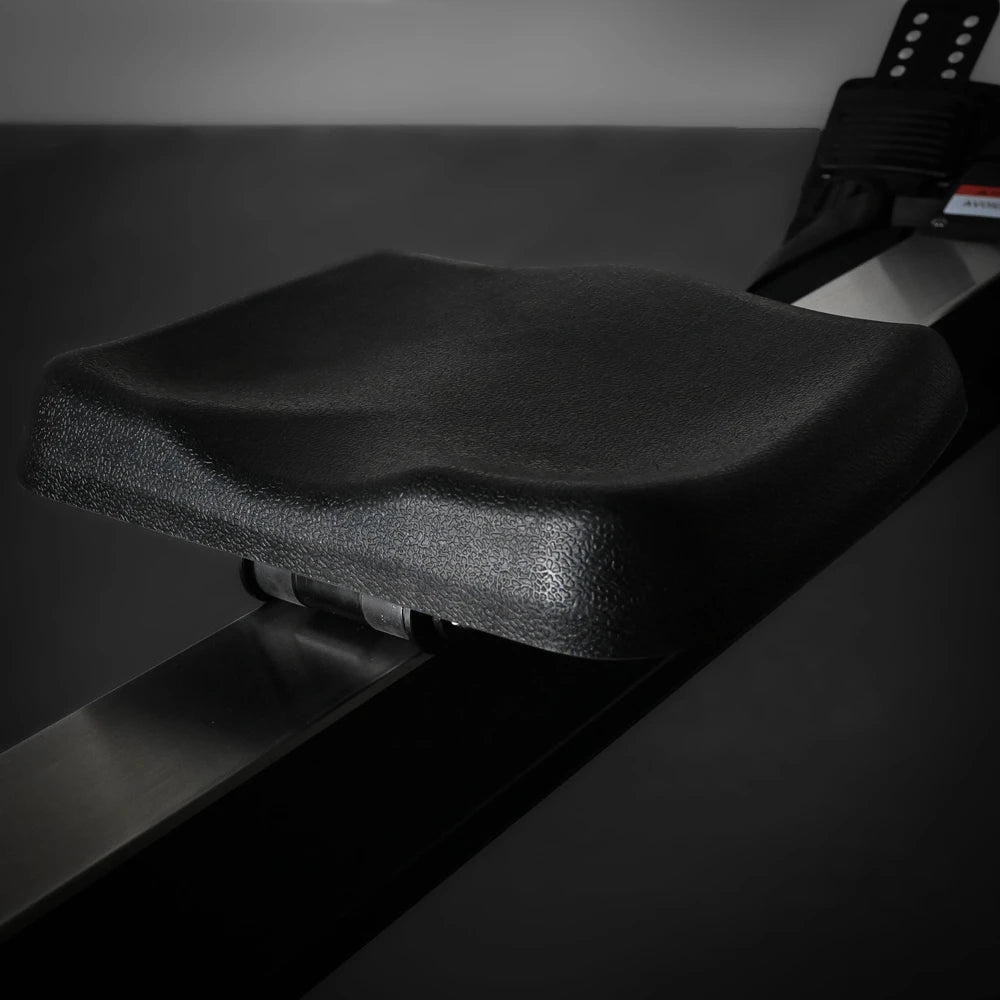 Black seat of a rowing erg machine on a dark background