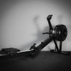 Commercial rowing erg machine with a black seat and digital display on a gray background