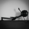 Black rowing machine against a gray wall