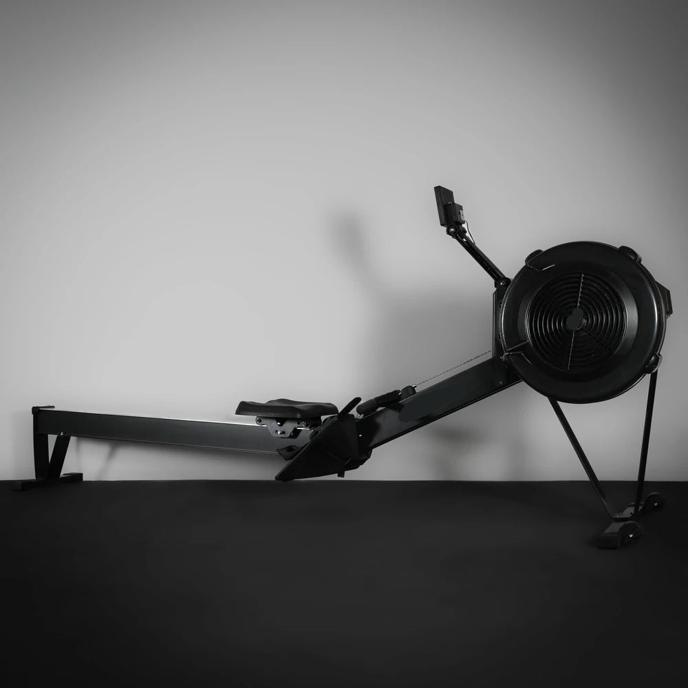 Black rowing machine against a gray wall