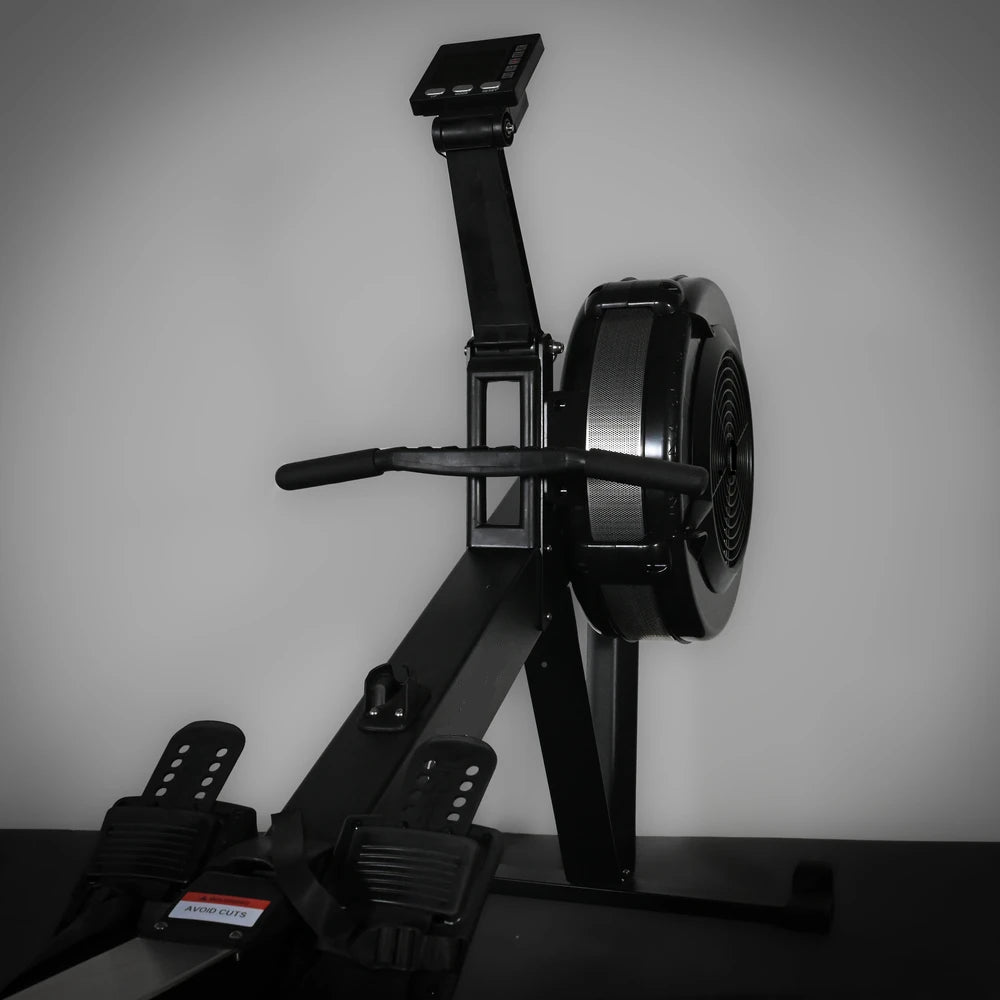 Black rowing machine against a gray wall