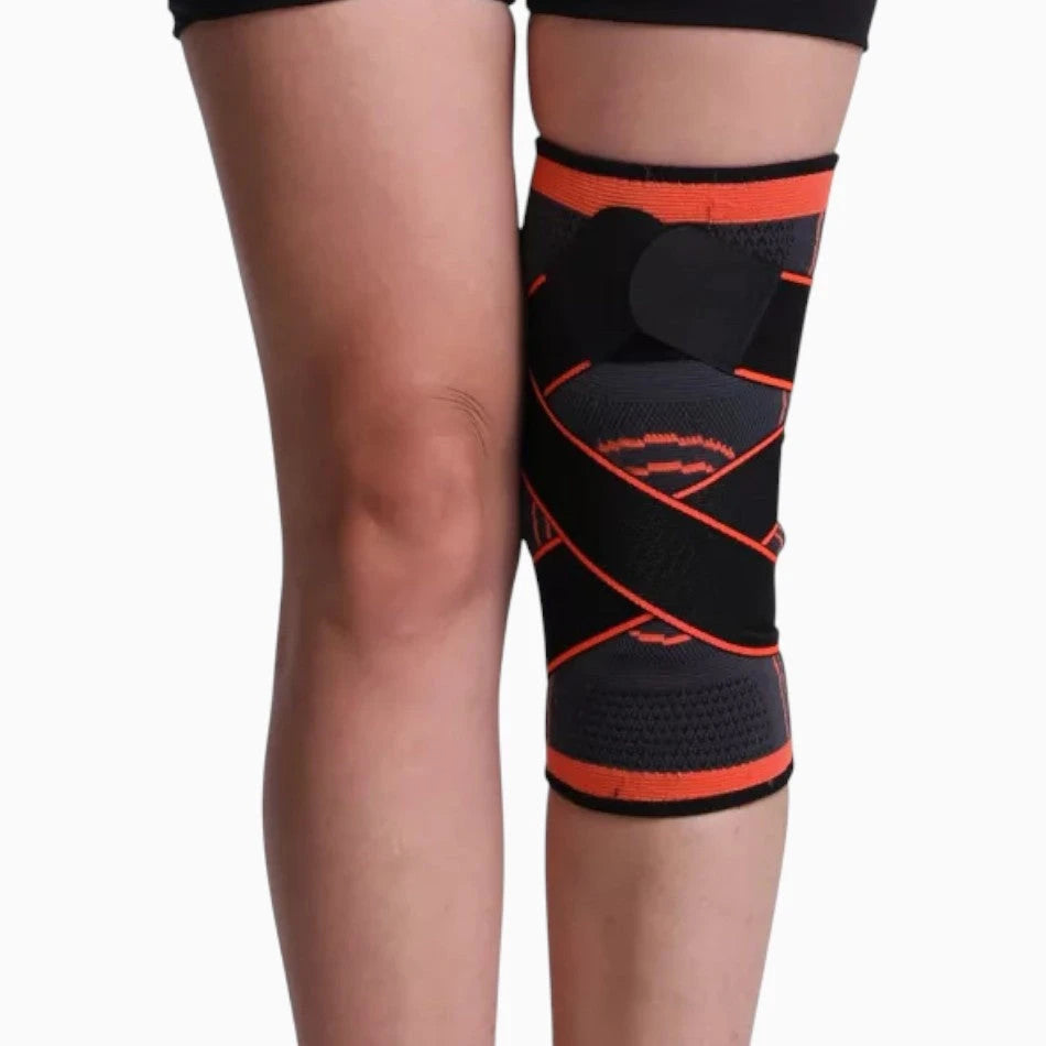 Black and orange knee brace on a person's leg against a white background