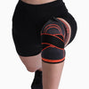 Black and orange knee brace on a person's knee against a white background