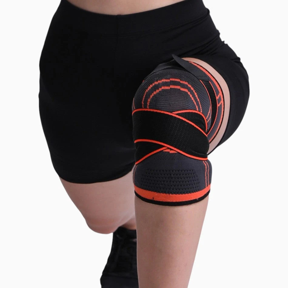 Black and orange knee brace on a person's knee against a white background