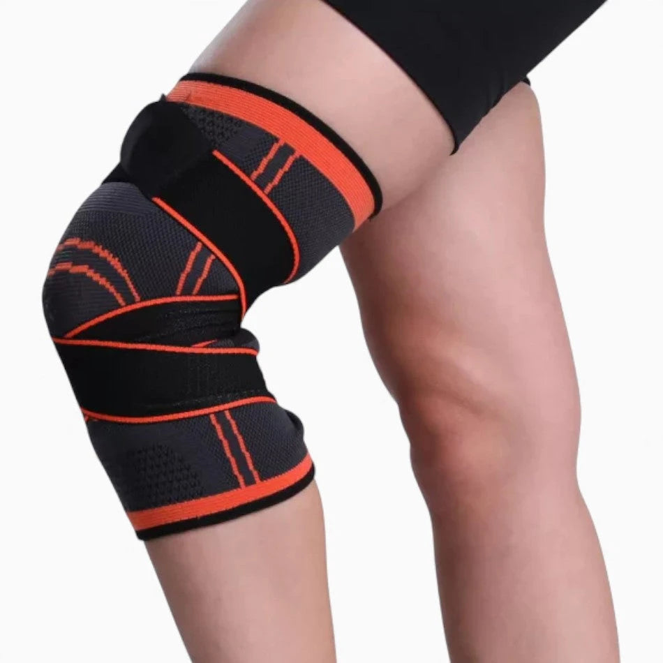 Black and orange knee brace on a person's knee against a white background