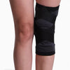 Black knee brace on a person's knee with a plain background