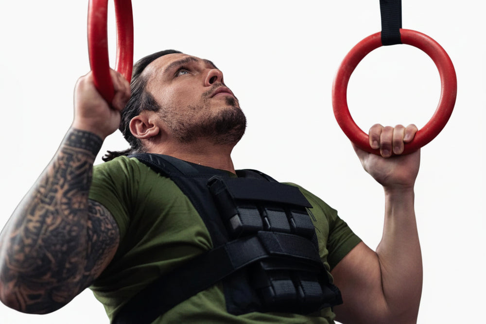 Man performing pull-ups with a weight vest on a white background