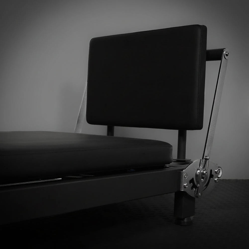 Black pilates reformer machine on a dark background