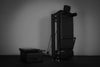 Black Pilates reformer and mat against a gray background