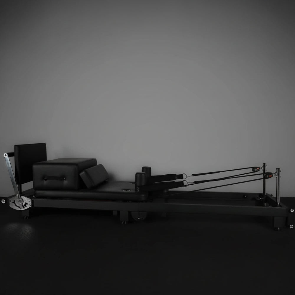 Pilates reformer machine against a plain wall