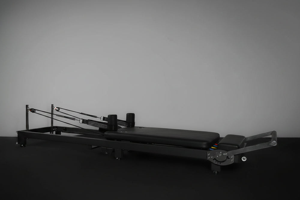 Black Pilates reformer on a dark background