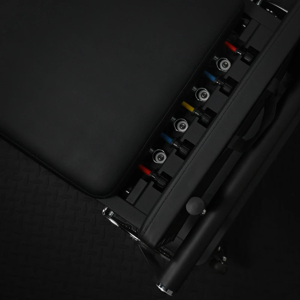 Close-up of mechanism on a pilates reformer machine on a dark background