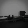 Black pilates exercise machine against a plain wall.