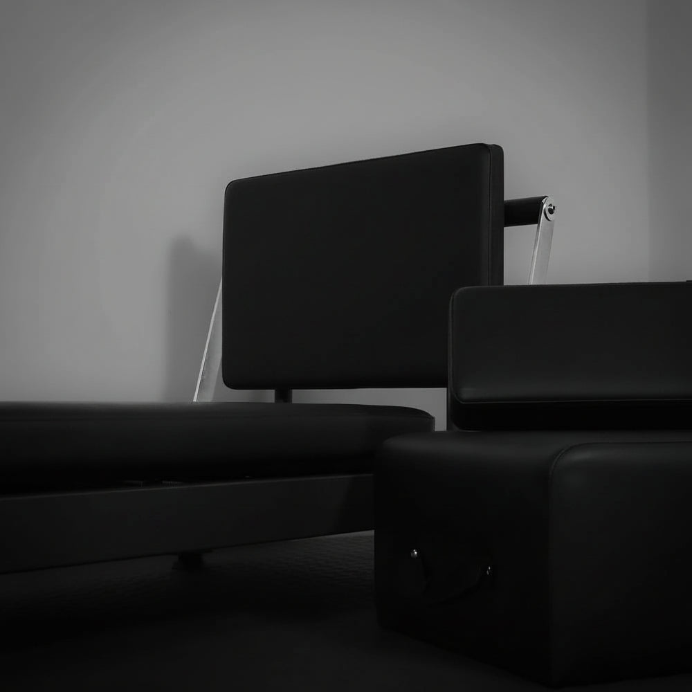 Black pilates exercise machine on a gray background