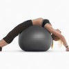 Person exercising on a black stability ball against a white background
