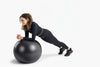 Woman exercising on a black exercise ball on a white background