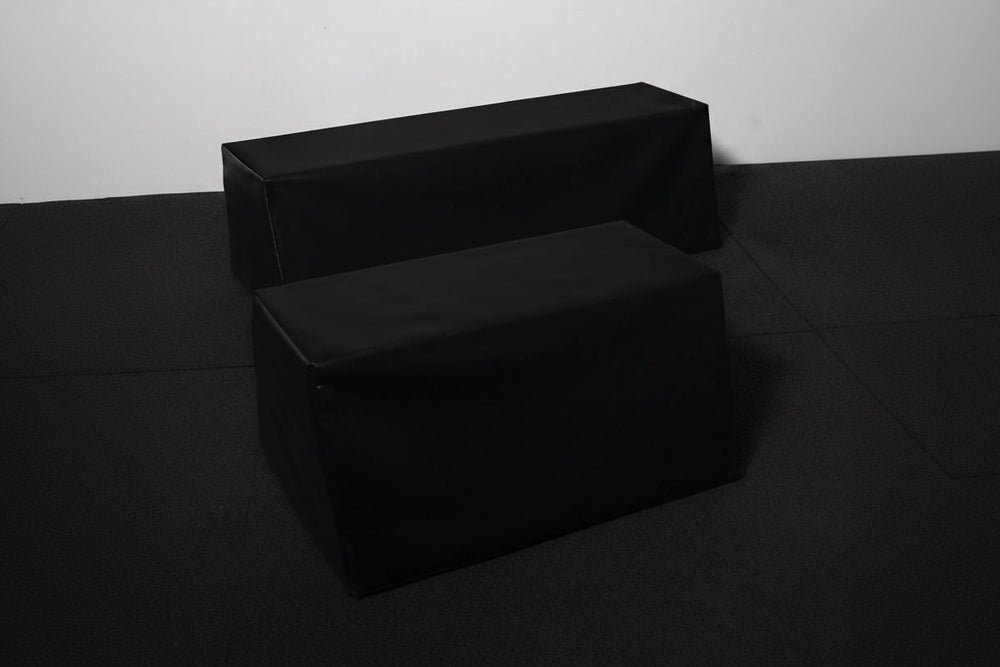 Two black gym wedges on a dark surface.