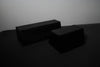 Two black commercial hip thrust benches on a dark background
