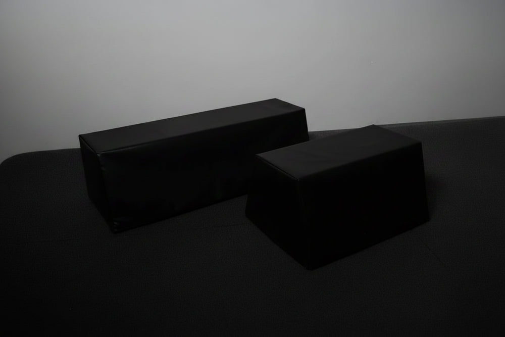 Two black commercial hip thrust benches on a dark background