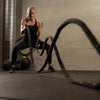 Woman exercising with battle ropes in a gym setting