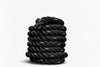 Coiled black battle rope on a white background