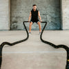Man exercising with battle ropes in a concrete indoor setting