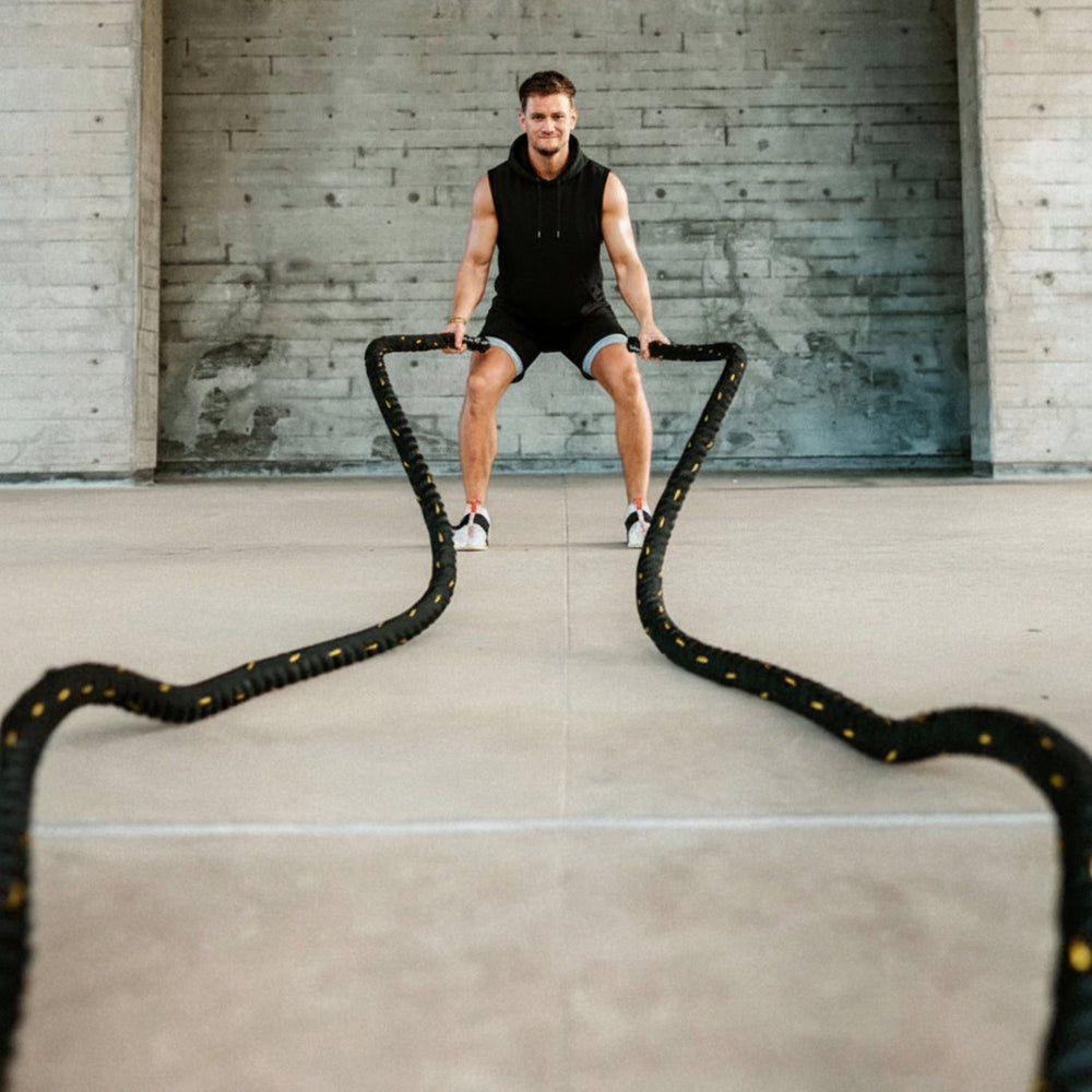 Man exercising with battle ropes in a concrete indoor setting