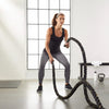 Woman exercising with battle ropes in a gym setting