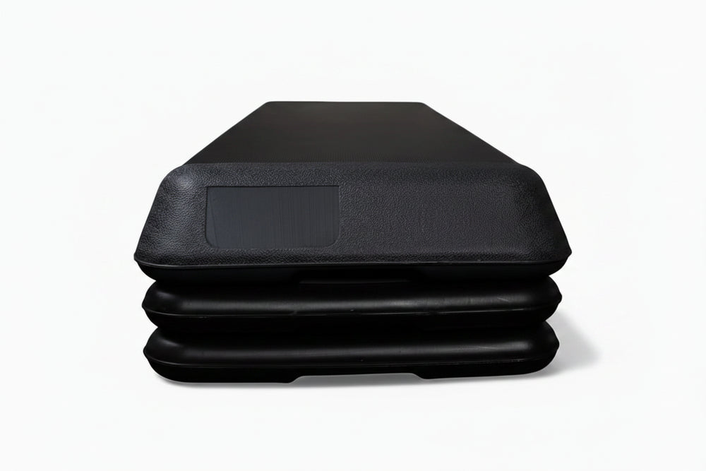 Black aerobics stepper with platform height adjusters on a white background