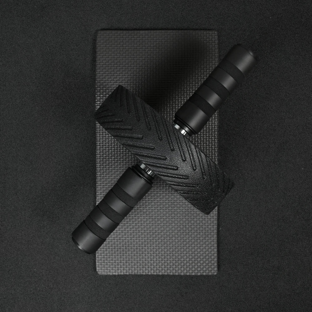 Black ab roller with textured handle on a black background