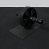 Black ab roller on a black mat with a gray background