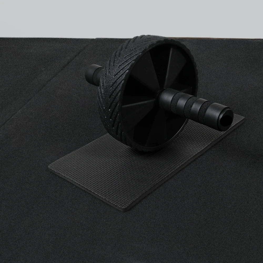 Black ab roller on a black mat with a gray background