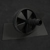 Black ab roller on a black mat with a dark background