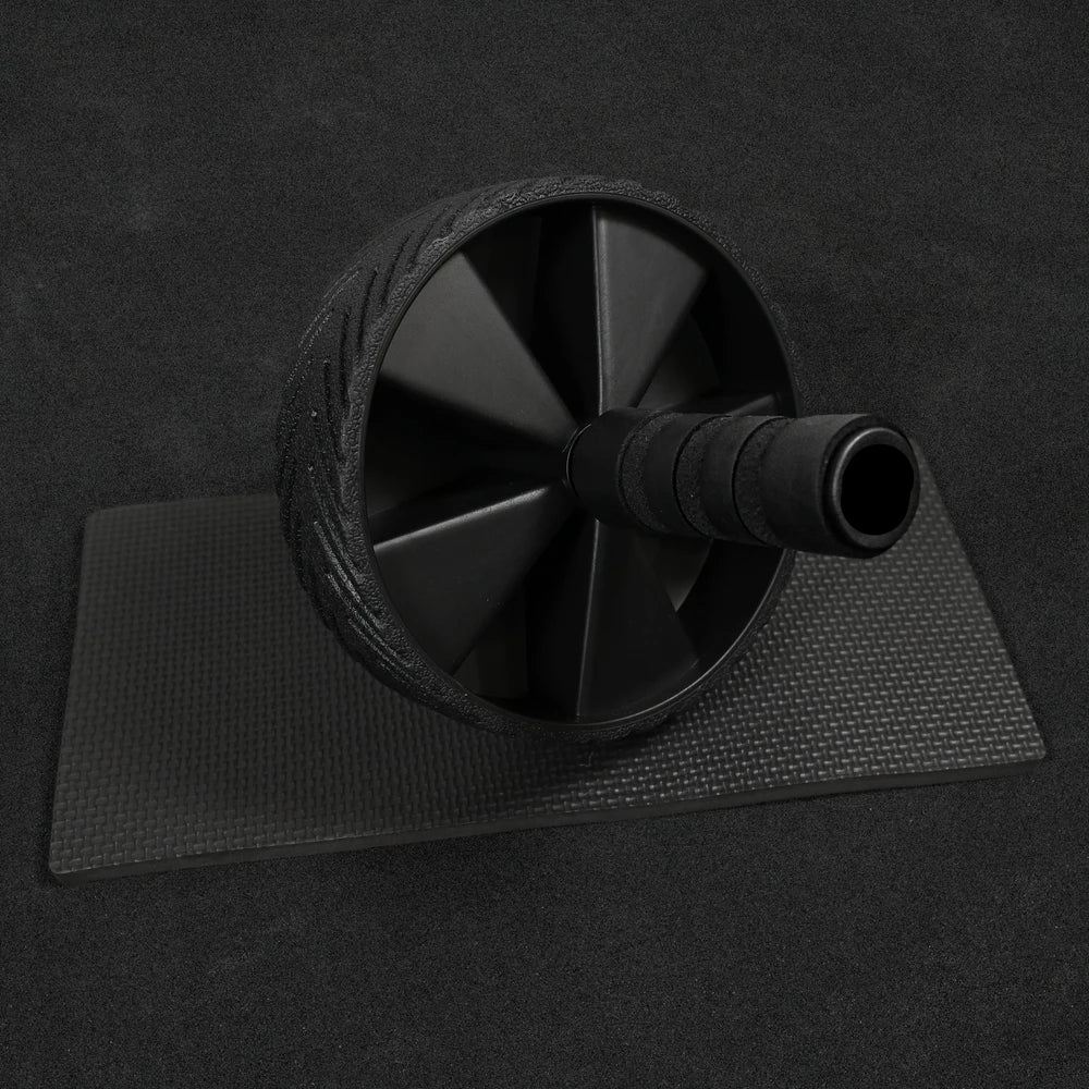 Black ab roller on a black mat with a dark background