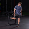 Man exercising with dumbbells on a bulgarian split squat stand in a gym setting