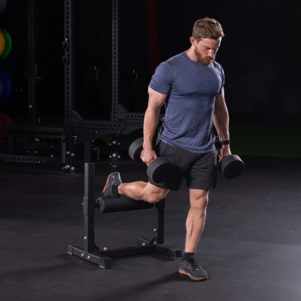 Man exercising with dumbbells on a bulgarian split squat stand in a gym setting